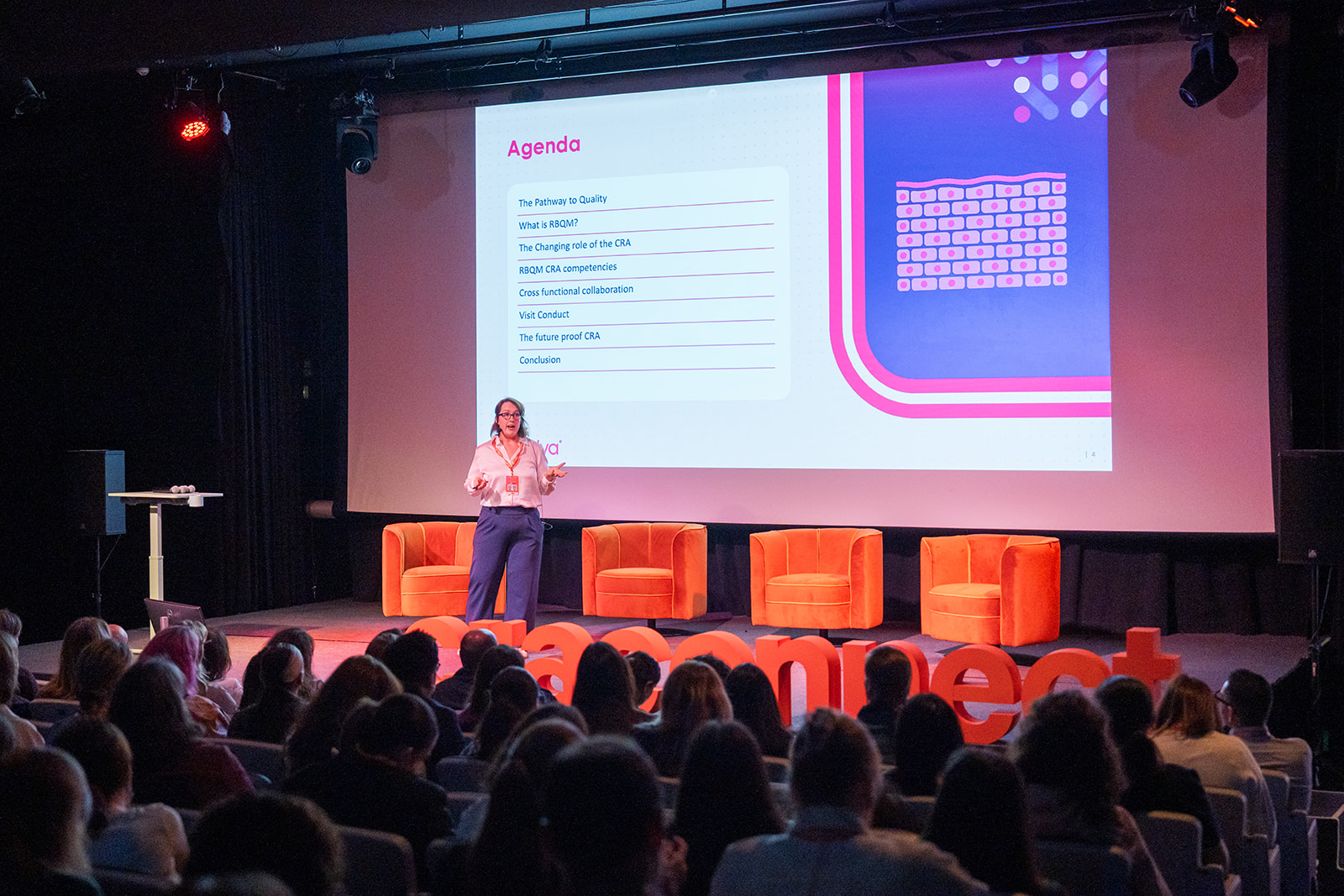 A speaker presenting on the CRACONNECT LIVE 2026 stage to a full room