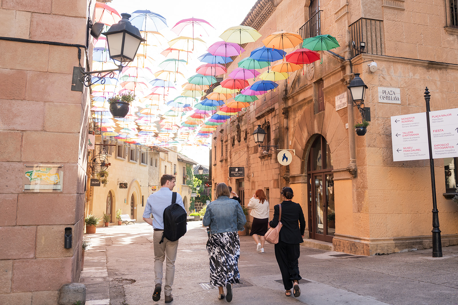 Attendees walking under the colourful umbrella street at Poble Espanyol, Barcelona